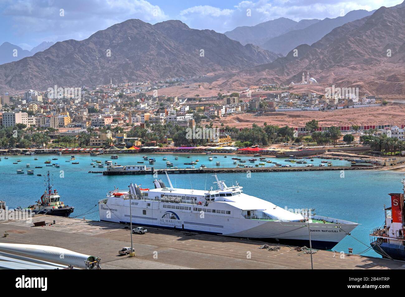 Fähre im Hafen gegen die Stadt mit Wasserfront und Bergen. Akaba Akaba, Golf von Akaba, Rotes Meer, Jordanien Stockfoto