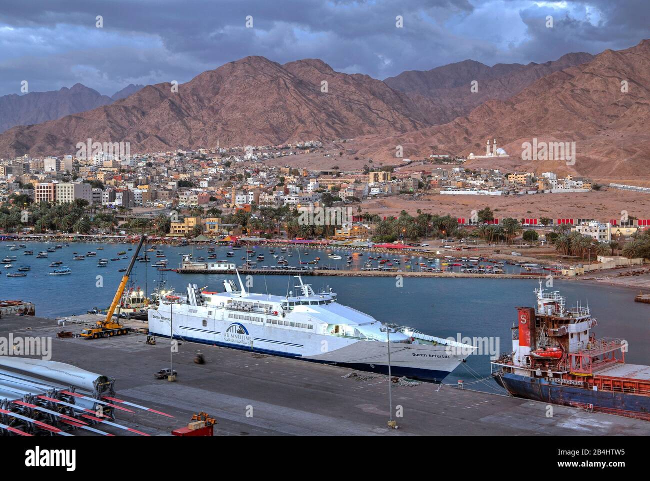 Fähre im Hafen gegen die Stadt mit Wasserfront und Bergen, Akaba Akaba, Golf von Akaba, Rotes Meer, Jordanien Stockfoto