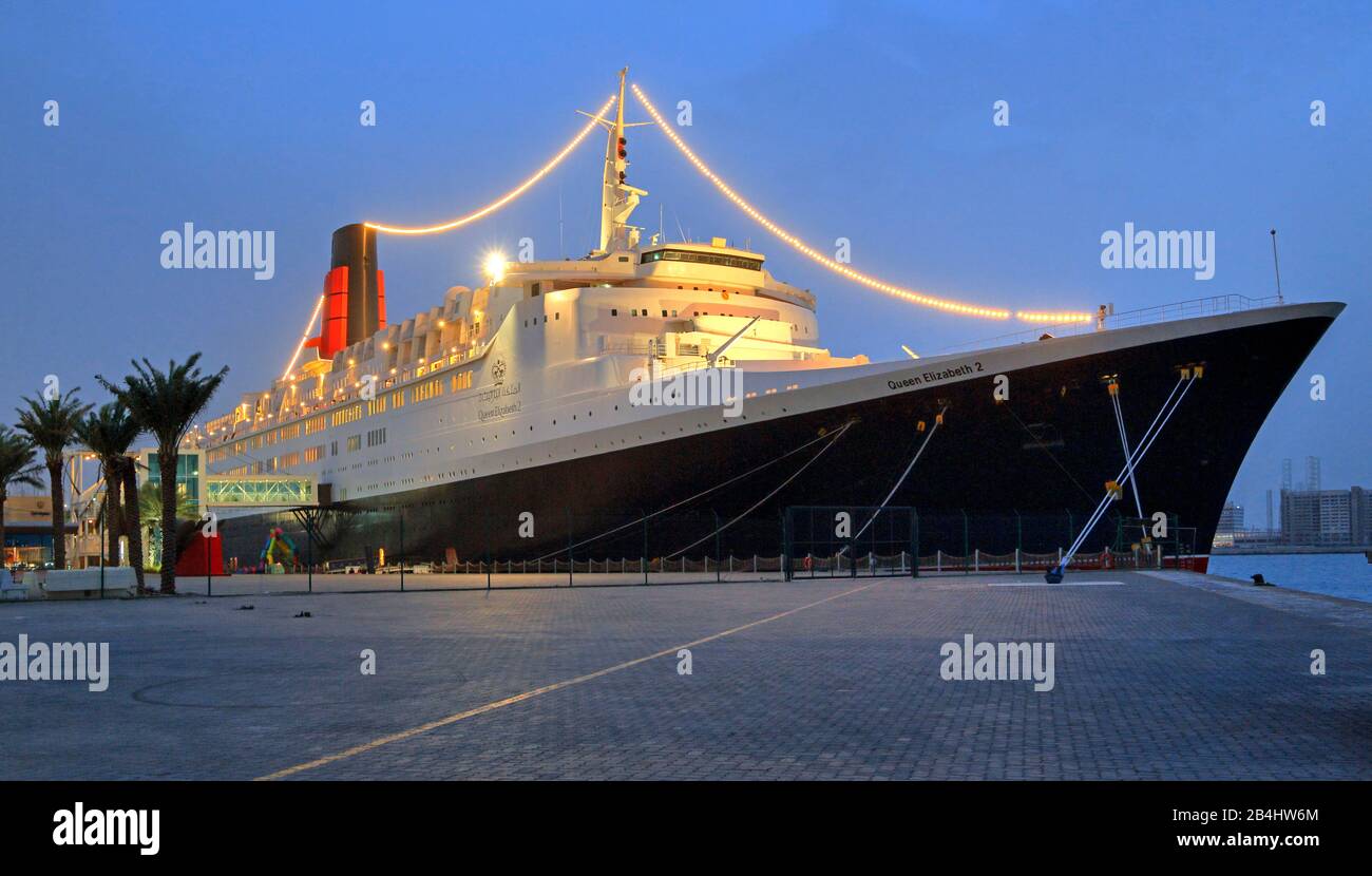 Beleuchtete Hotel- und Museumsschiff Queen Elizabeth 2 (QE2) am Pier in der Dämmerung, Dubai, Persischer Golf, Vereinigte Arabische Emirate Stockfoto