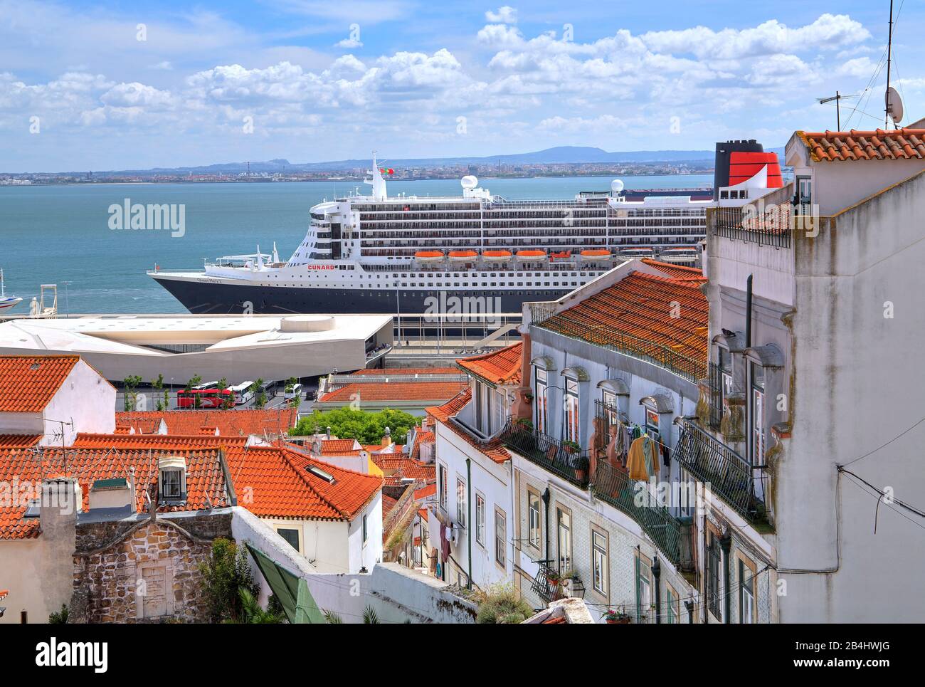 Altstadtdächer mit dem Transatlantikliner Queen Mary 2 im Hafen am Tejo, Lissabon, Portugal Stockfoto