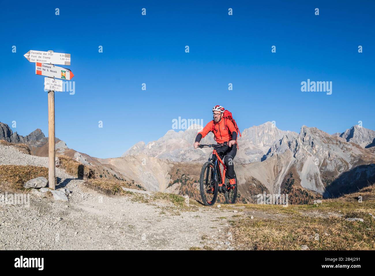 Ein Mann mit ebike MTB auf den Gleisen im San Nicolò Tal mit Marmolada auf dem Hintergrund, Trentino, Dolomitenes, Italien Stockfoto