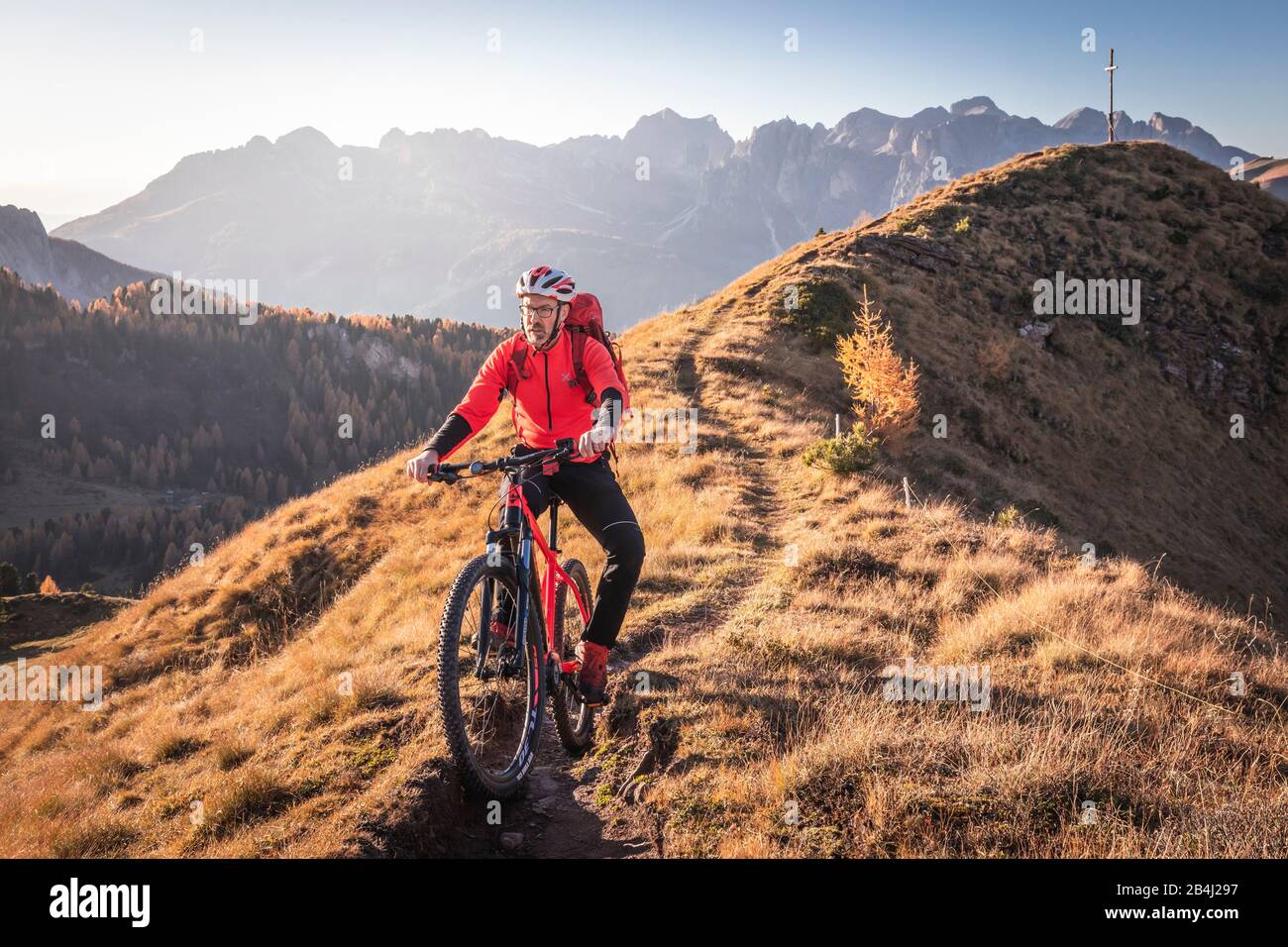 Ein Mann fährt auf den Gleisen im Tal von San Nicolò, Fassa, Trentino, in den Bergen, in Italien mit einem Fahrrad MTB Stockfoto