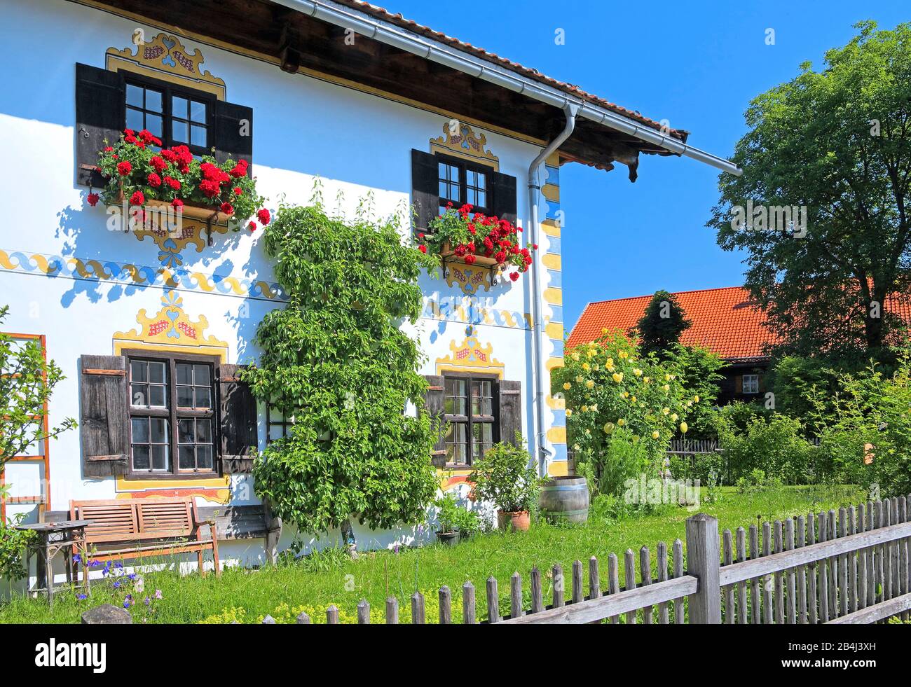 Seitenansicht eines oberbayerischen Landhauses mit Garten- und Blumenarrangements in Ohlstadt, Loisachtal, Oberbayern, Bayern, Deutschland Stockfoto