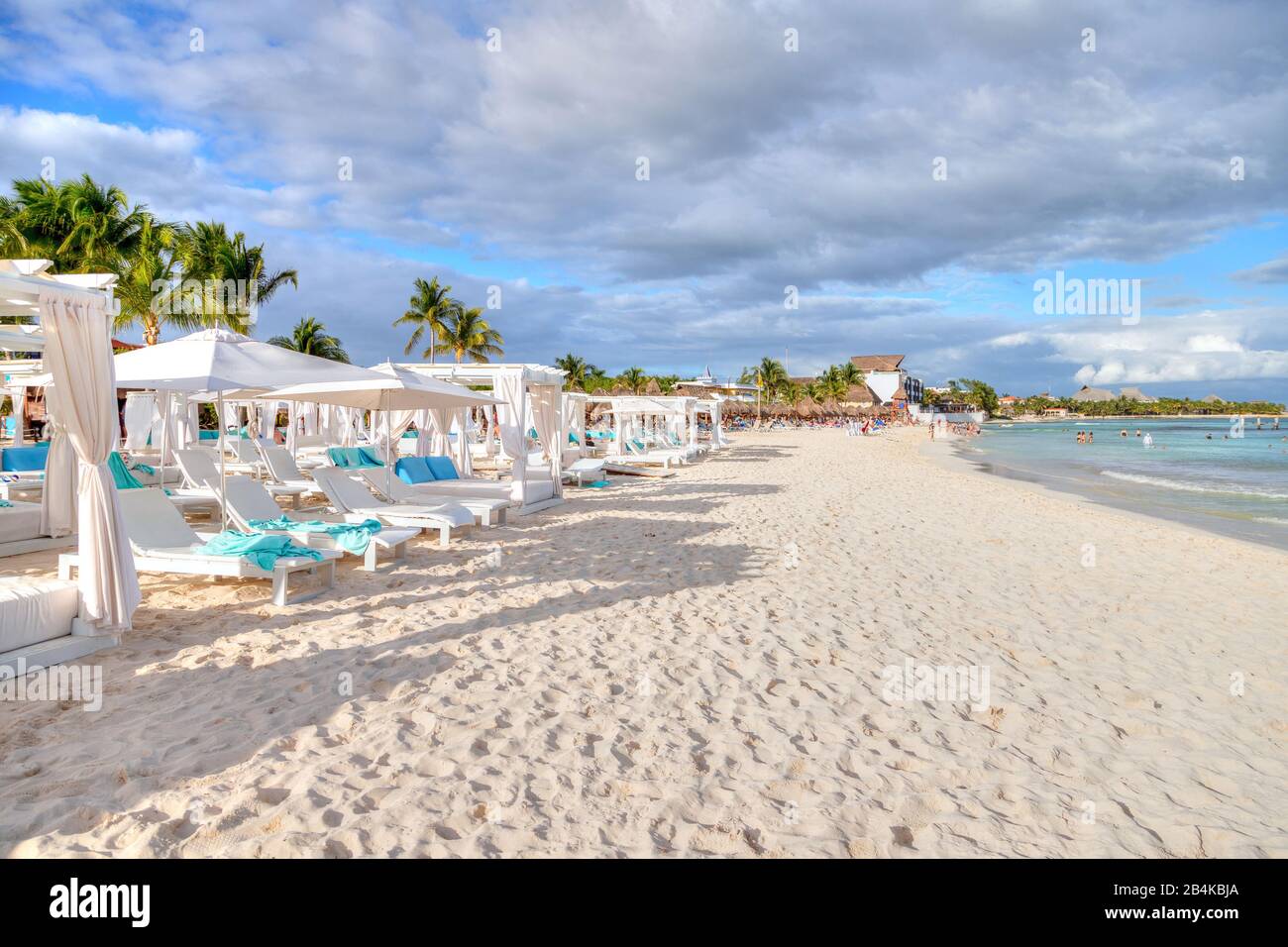 Reihen von Betten und Stühlen an einem sonnigen, sandigen tropischen Strand an der karibischen Küste von Cancun, Mexiko. Konzept für Sommerurlaub oder Winterurlaub. Stockfoto