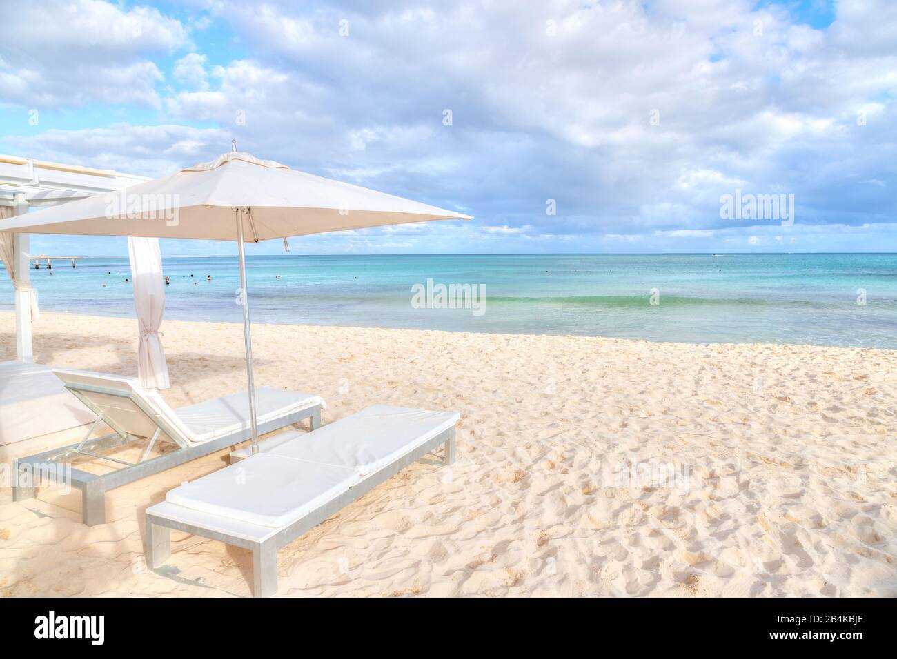 Liegestuhlbetten und Sonnenschirm am weißen Strand an der karibischen Küste der Riviera Maya in Cancun, Mexiko. Stockfoto