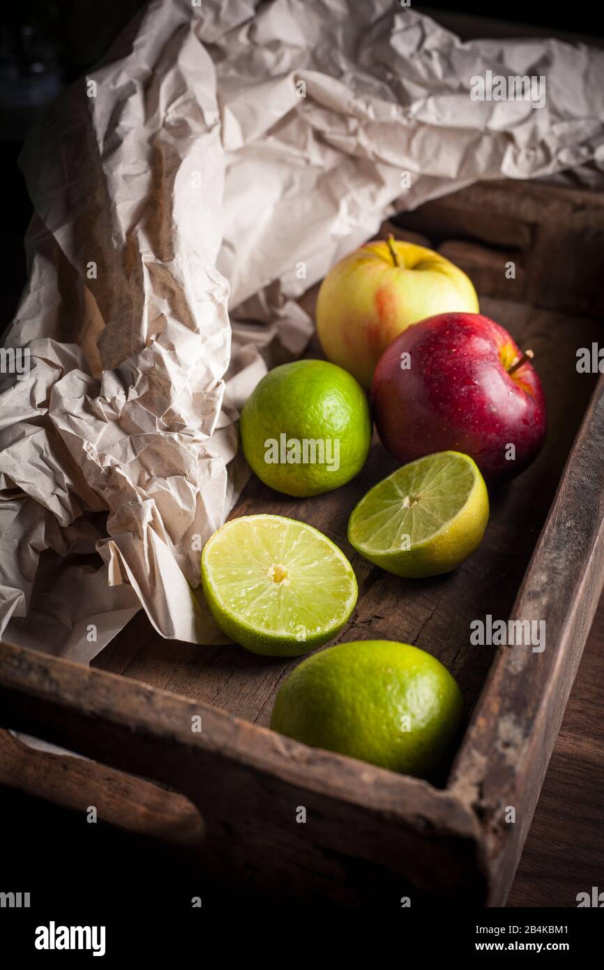 Äpfel und Limes in Holzkiste Stockfoto