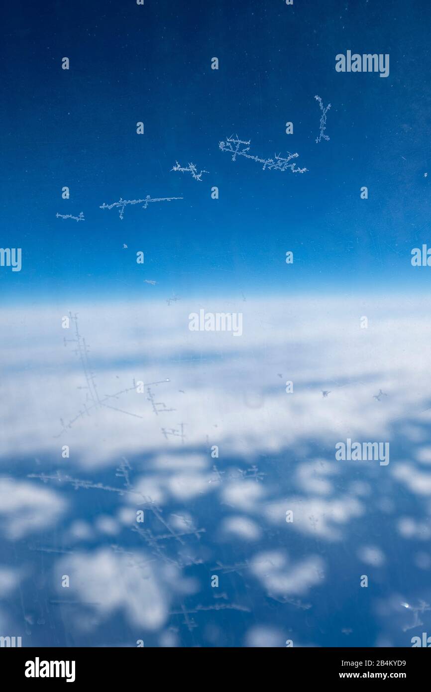 Eiskristalle am Flugzeugfenster vor blauem Himmel Stockfoto