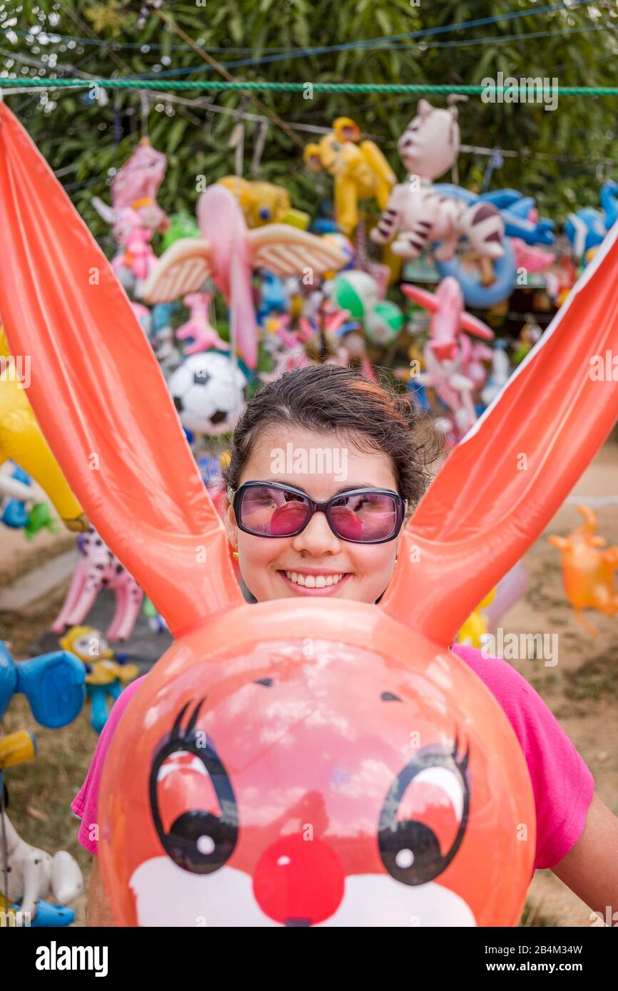 Ein Mädchen hat Spaß inmitten vieler Ballontiere Stockfoto