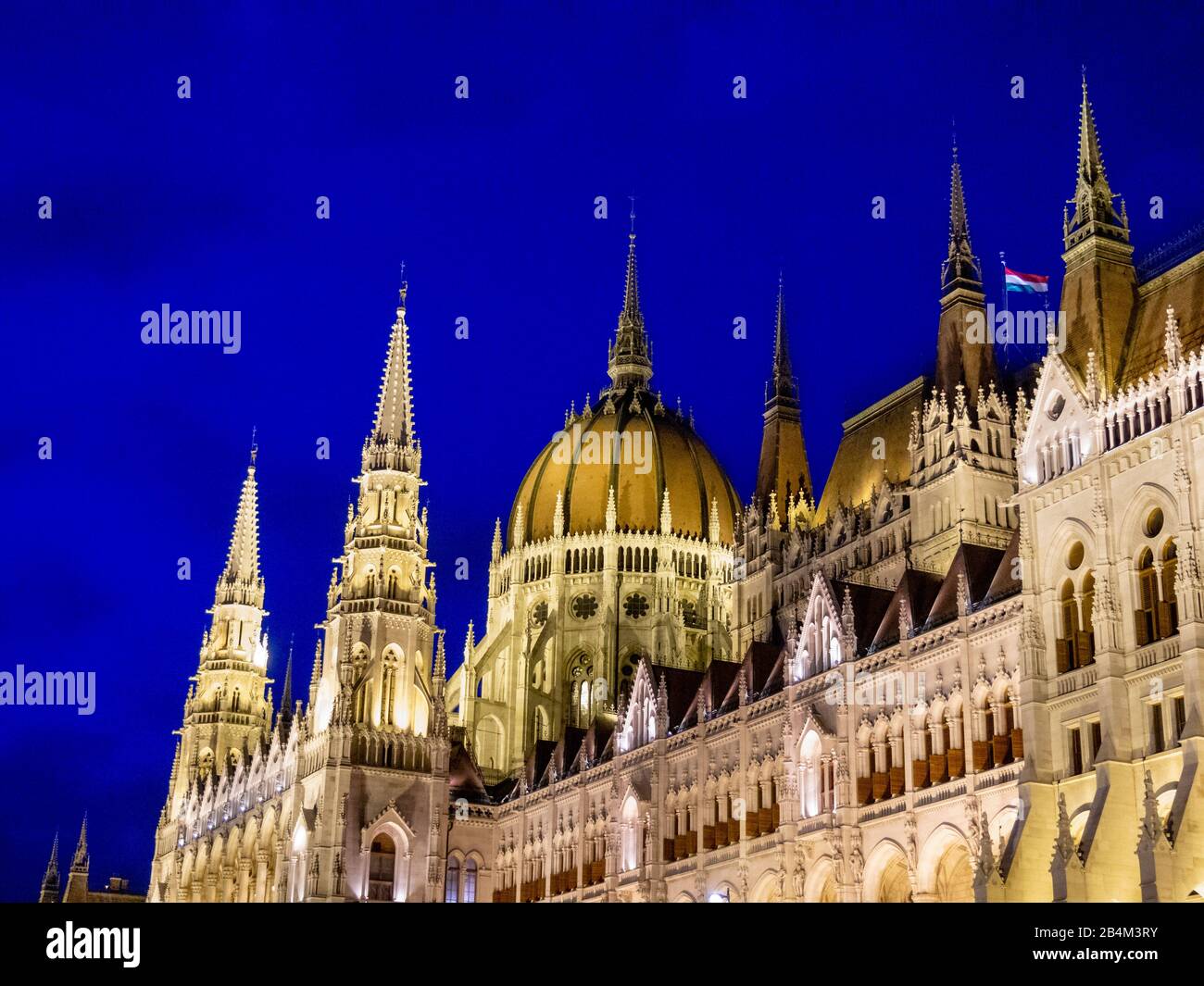 Der Zentraldom der ungarischen Parlamentsgebäude: Flutlicht in der Abenddämmerung leuchten die Türme und die Kuppel der riesigen ungarischen Parlamentsgebäude gegen den dunkelblauen Nachthimmel. Stockfoto