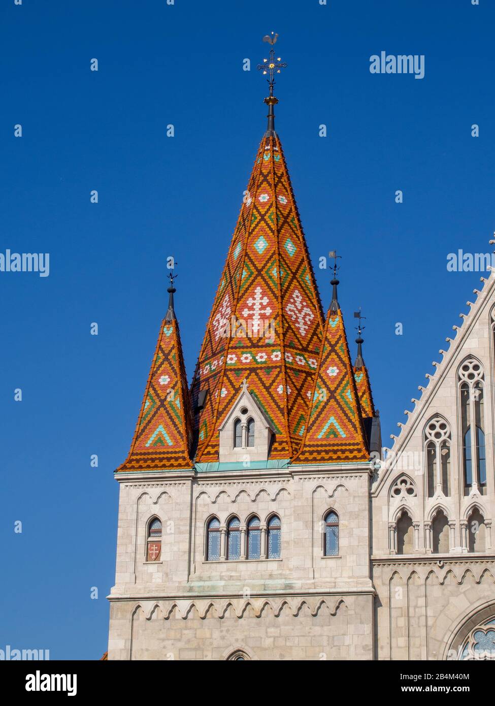 Glühende Fliesen der Matthias Kirche: Die atemberaubenden Keramikfliesen der Matthias Kirche leuchten in der Nachmittagsonne gegen das tiefblaue eines wolkenlosen Himmels. Stockfoto