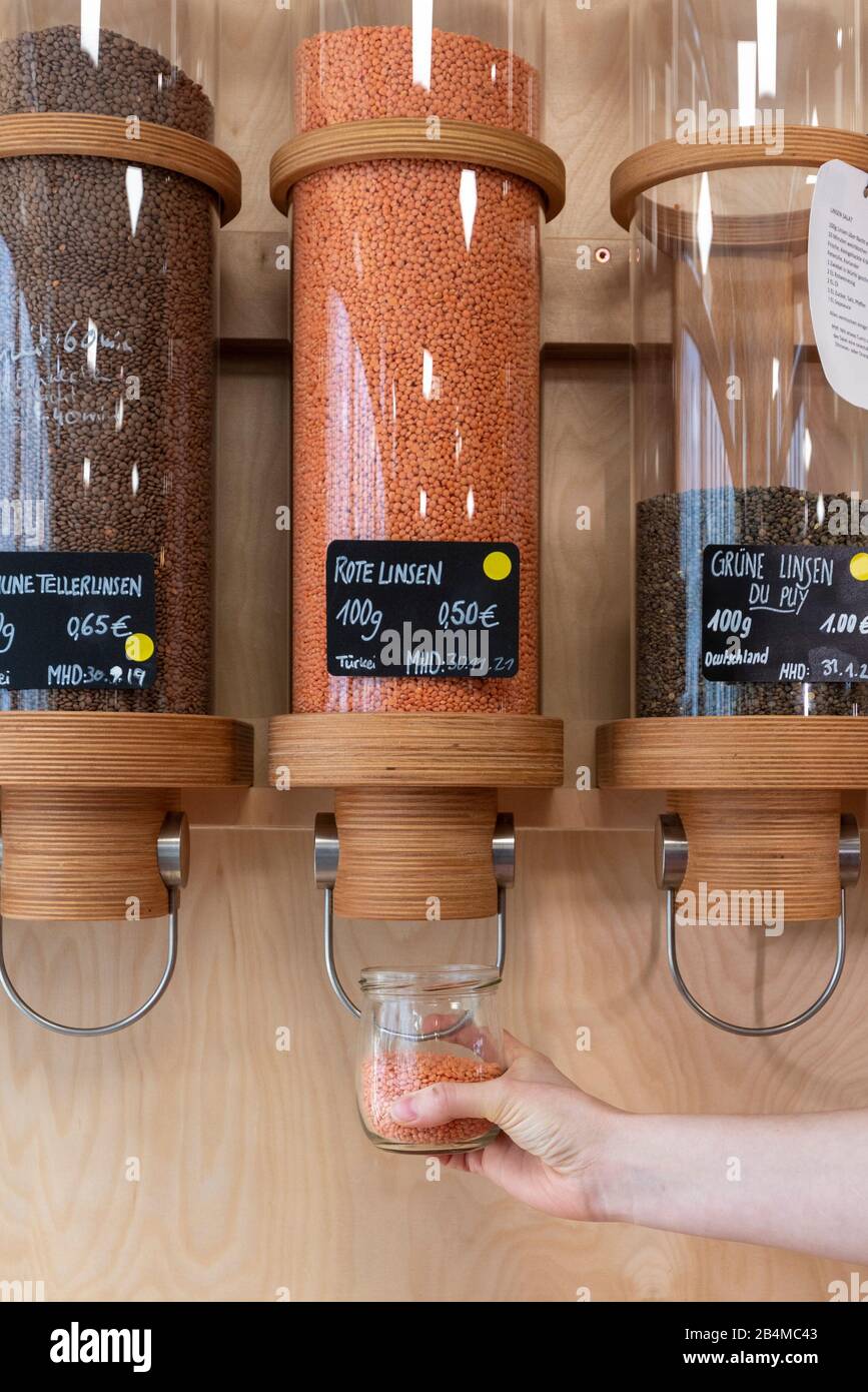 Eine Frau Füllt in einem Unverpacktladen hat Linsen ab. Stockfoto