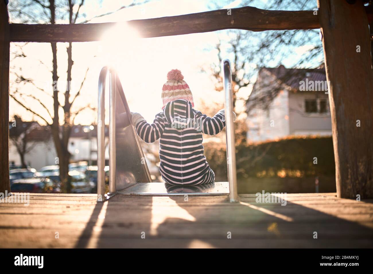 Kleines Kind auf einem Objektträger im Sonnenlicht, von hinten Stockfoto