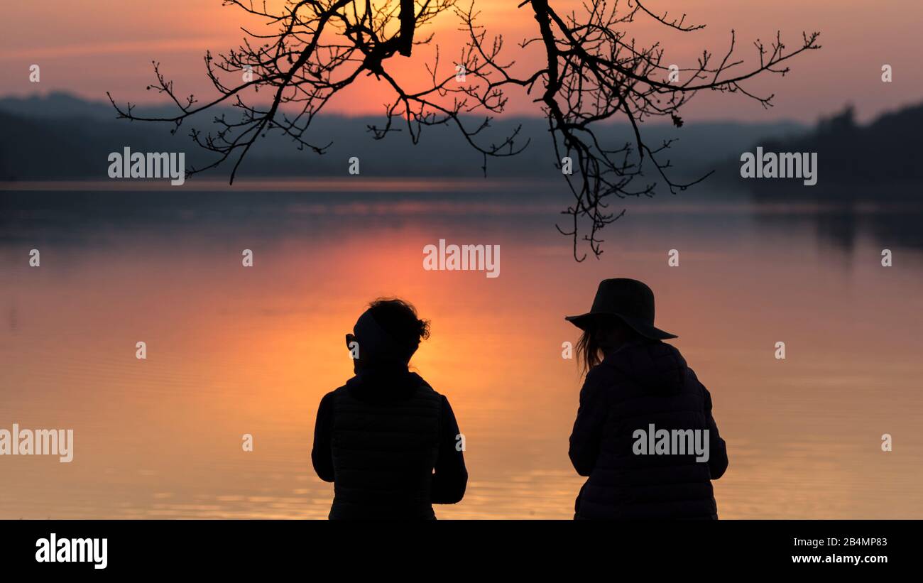 Sommer in Bayern. Eindrücke aus dem Alpenvorland: Silhouetten zweier Frauen am Staffelsee bei Sonnenuntergang Stockfoto