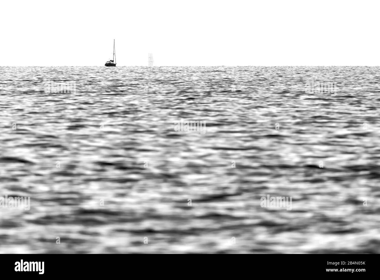 Ein Segelschiff mit drei Masten am Horizont im Mittelmeer. Leichte Wellen im Vordergrund. Stockfoto