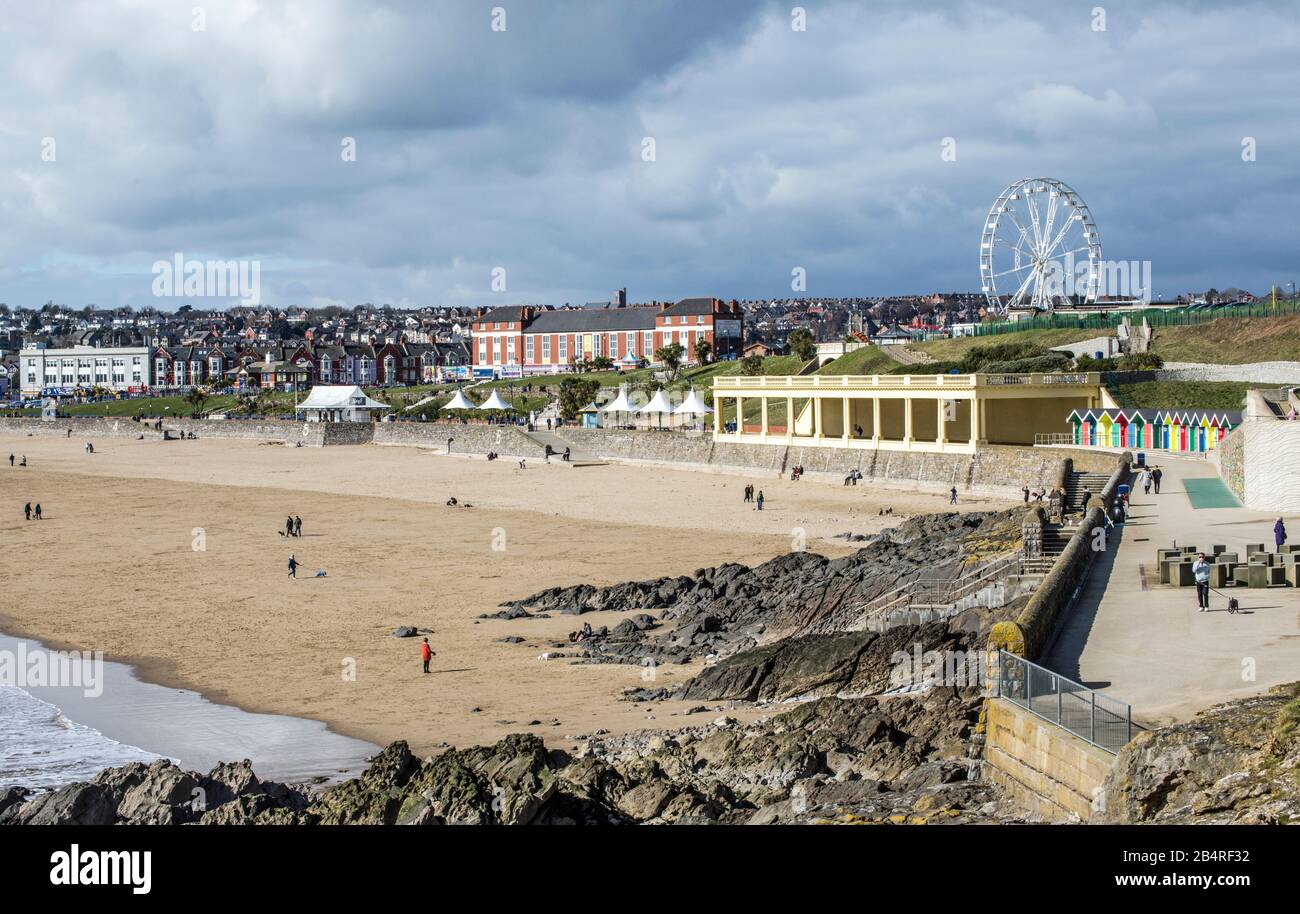 Blick auf die Whitmore Bay auf Barry Island an einem Märzmorgen, der den Strand, die Menschen, das Big Wheel und mehr zeigt, in Südwales an der Küste. Stockfoto