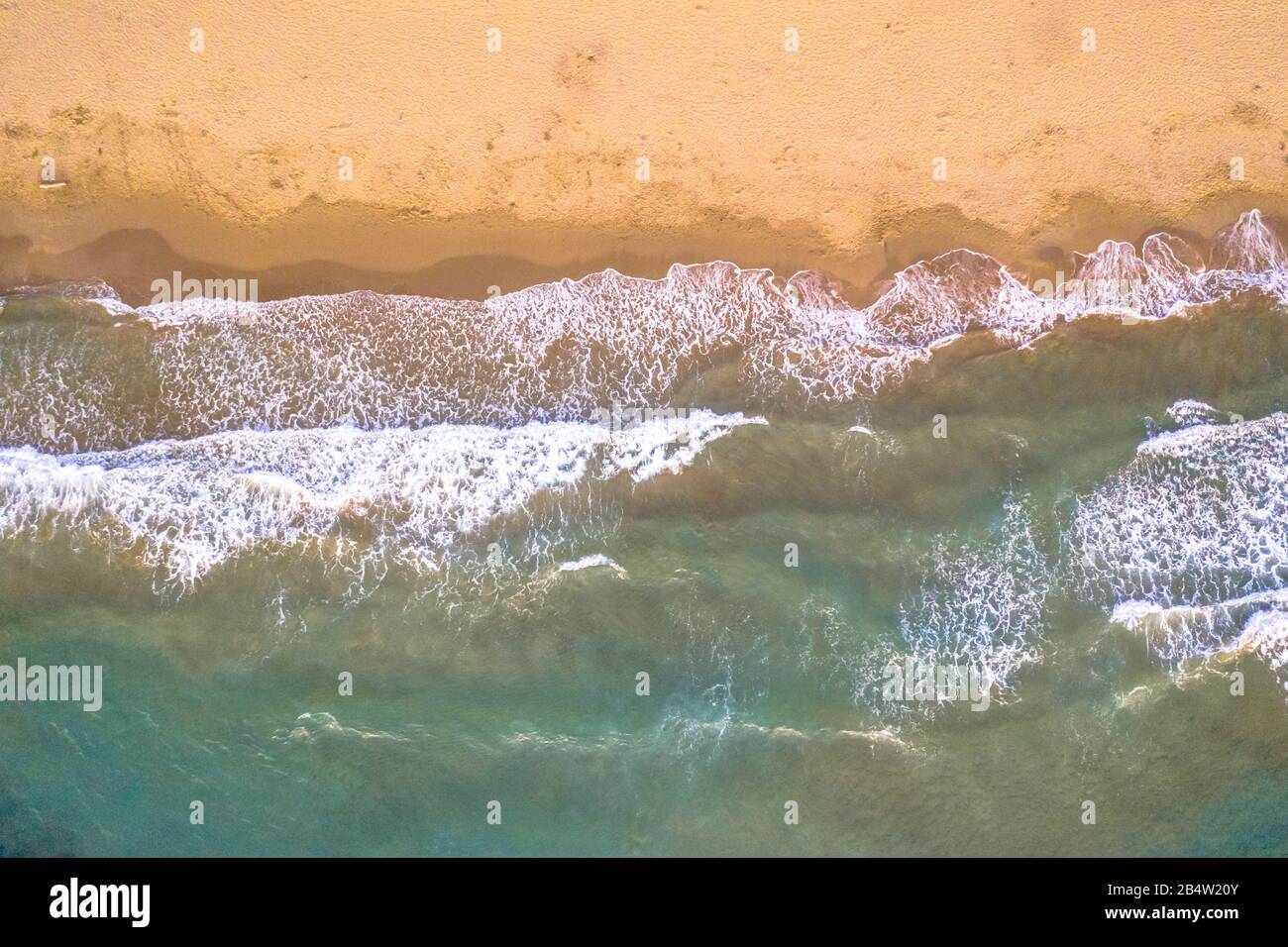 Von oben Blick auf die Meereswellen des Wassers am goldfarbenen Strand von Korsika, Frankreich. Stockfoto