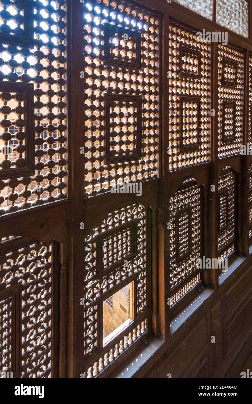 Winkelansicht von verzierten Fenstern aus verschachteltem Holz - Mashrabiya - in Steinwand am verlassenen Gebäude Stockfoto