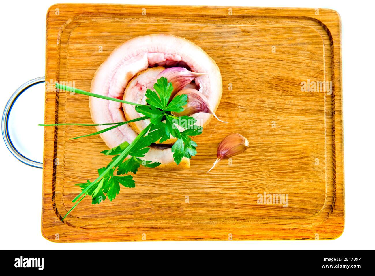 Schweinebauch mit Knoblauch und Petersilie auf Holzbrett isoliert auf weißem Grund. Stockfoto