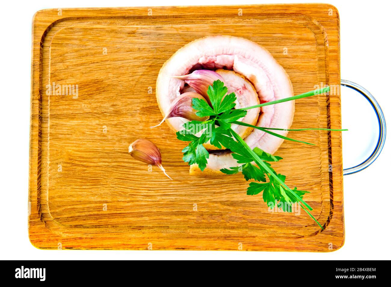 Schweinebauch mit Knoblauch und Petersilie auf Holzbrett isoliert auf weißem Grund. Stockfoto