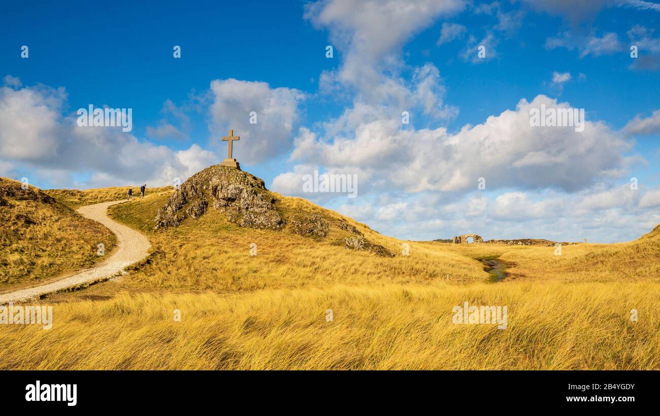 Ein Blick auf den Küstenweg und die Ruinen der St. Dwynwen Kirche und die modernen und keltischen Kreuze auf Llanddwyn Insel, Anglesey Stockfoto