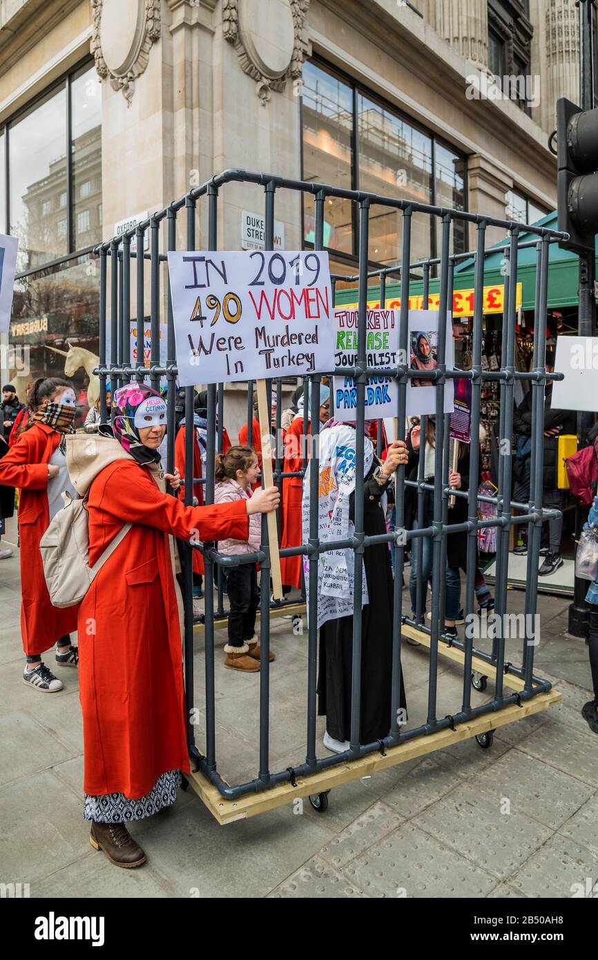 London, Großbritannien. März 2020. Türkische Frauen bringen ein Mock ins Gefängnis, um die Freiheit einer türkischen Journalistin zu fordern, sowie ein Ende der schlechten und unfairen Behandlung von Frauen im Allgemeinen - Millionen Frauen Erheben sich im März, um sich an Frauen und Mädchen zu erinnern, die getötet wurden. Die diesjährigen Themen waren "Nie Vergessen" & "Gerechtigkeit" - "Wir werden nicht zum Schweigen gebracht! Wir werden nicht vergessen!". Die Marscher wurden gebeten, etwas Rotes zu tragen - die Farbe des Blutes, "das Blut unserer Schwestern, die in den Händen männlicher Gewalt ermordet und vergewaltigt wurden." Credit: Guy Bell/Alamy Live News Stockfoto