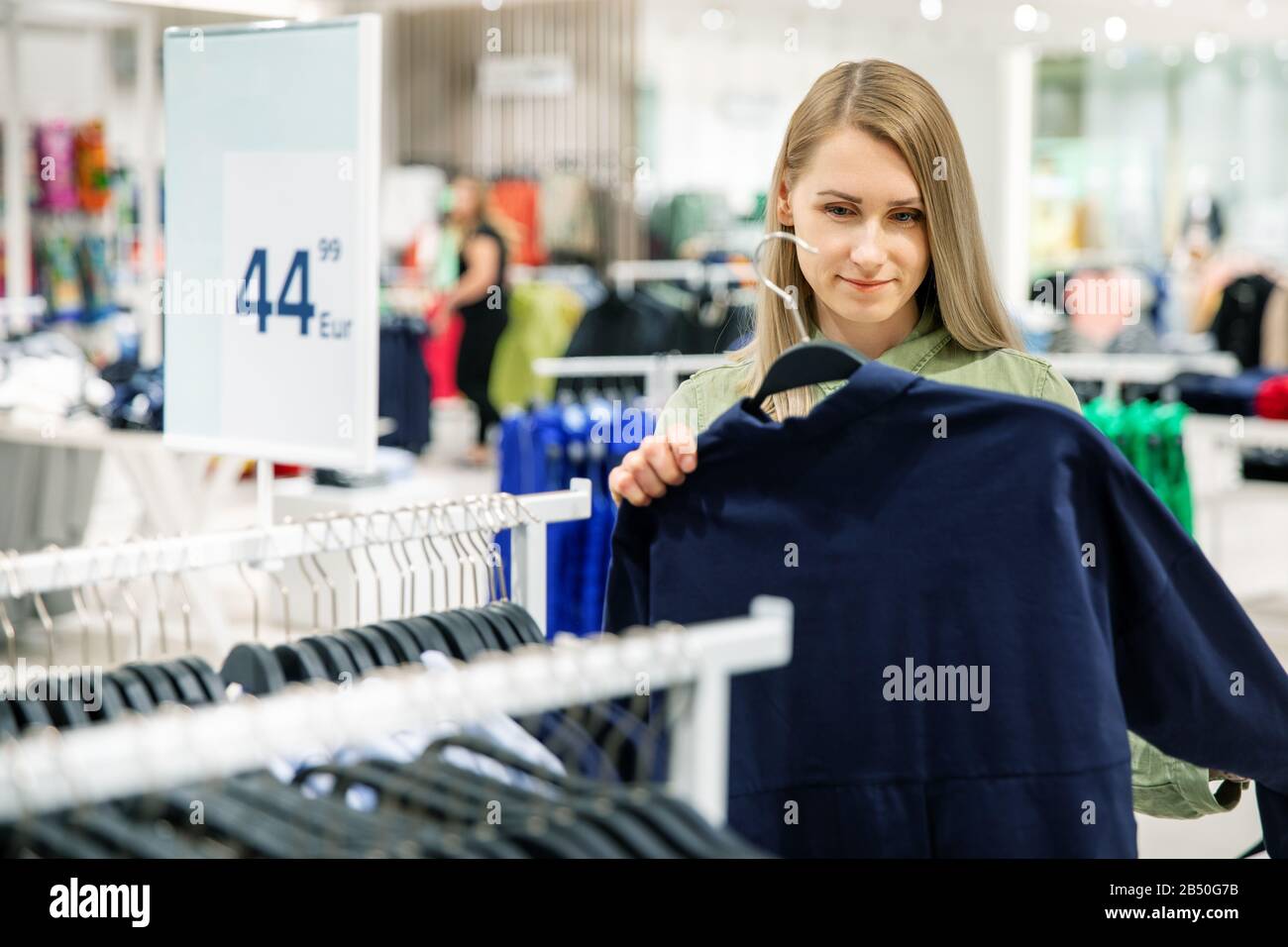 Junge Frau hat einen Shopping-Tag und sucht neue Kleidung im Bekleidungsgeschäft Stockfoto