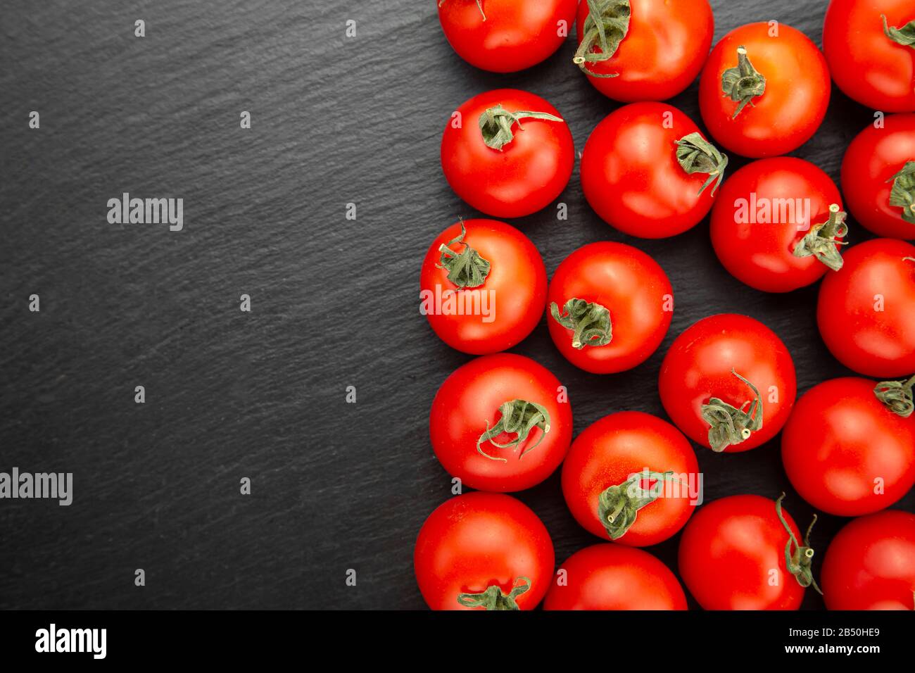 Frische Tomaten auf einem schwarzen Schneidebrett. Gesunde Ernährung. Stockfoto