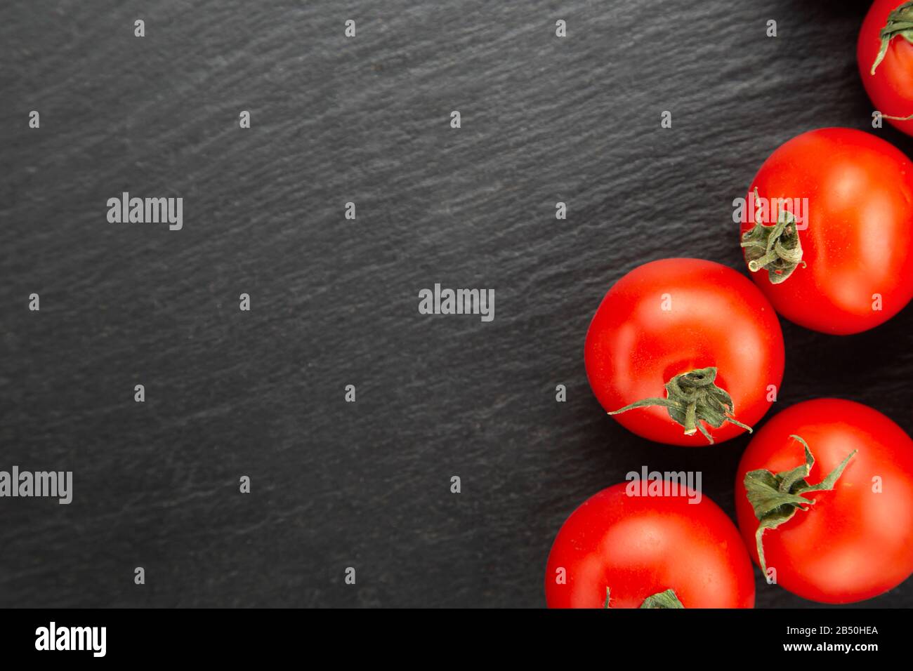 Frische Tomaten auf einem schwarzen Schneidebrett. Gesunde Ernährung. Stockfoto