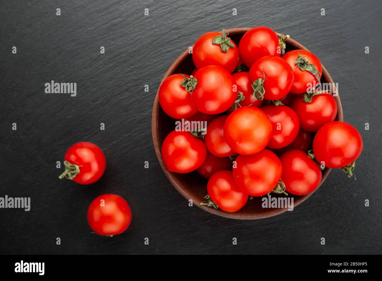 Frische Tomaten in einer Schüssel auf schwarzem Hintergrund. Ansicht von oben. Stockfoto