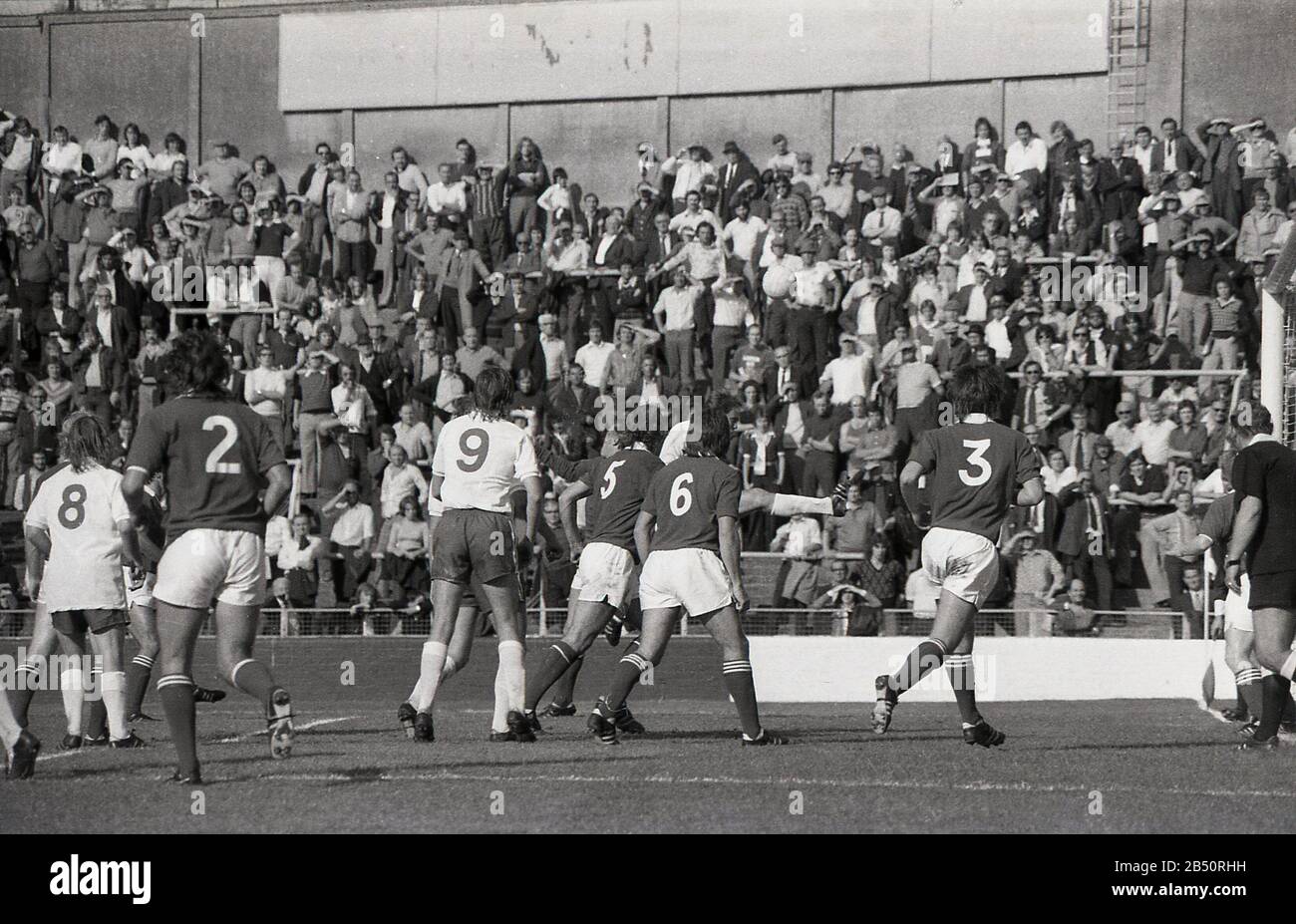 1970er Jahre, historisch, Fans beobachten ein Fußballspiel auf den Terrassen, im Millwall, FC, South London, England, UK. Fußballterrassen sind eine Reihe von Betontreppen mit Metallbarrieren an zahlreichen Stellen, um zu verhindern, dass sich Personen den Hang hinunterbewegen. Stockfoto