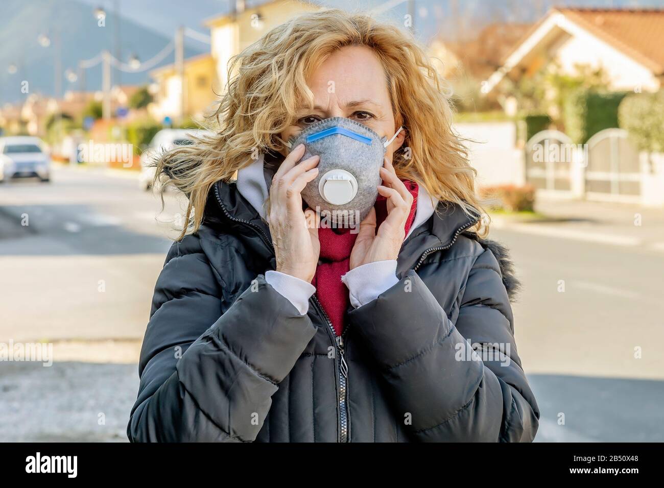 Weiße Frau geht mit der Schutzmaske in den Zeiten des Coronavirus "Covid - 19" auf die Straße, was viele Menschen betrifft Stockfoto