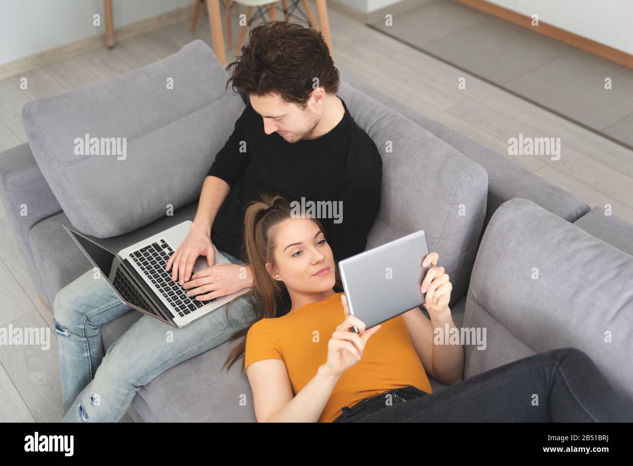 Verbinden Sie das schnelle Internet zu Hause mit Laptop und digitalem Tablet. Frau und Mann auf dem Sofa im Wohnzimmer Stockfoto