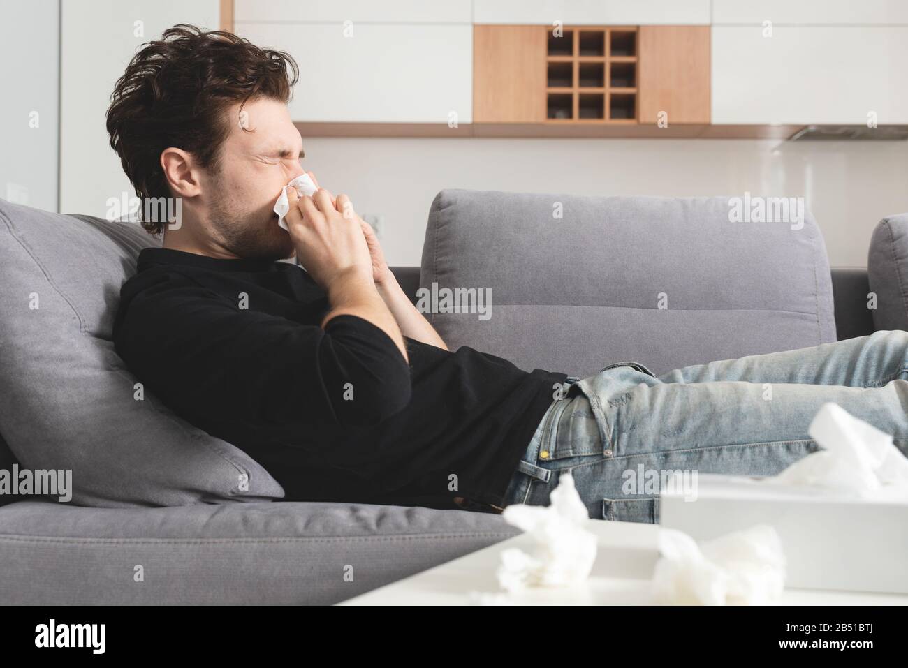 Kranker Mann auf Sofa liegend und Nase wehend. Gesundheitswesen, Krankheitskonzept Stockfoto