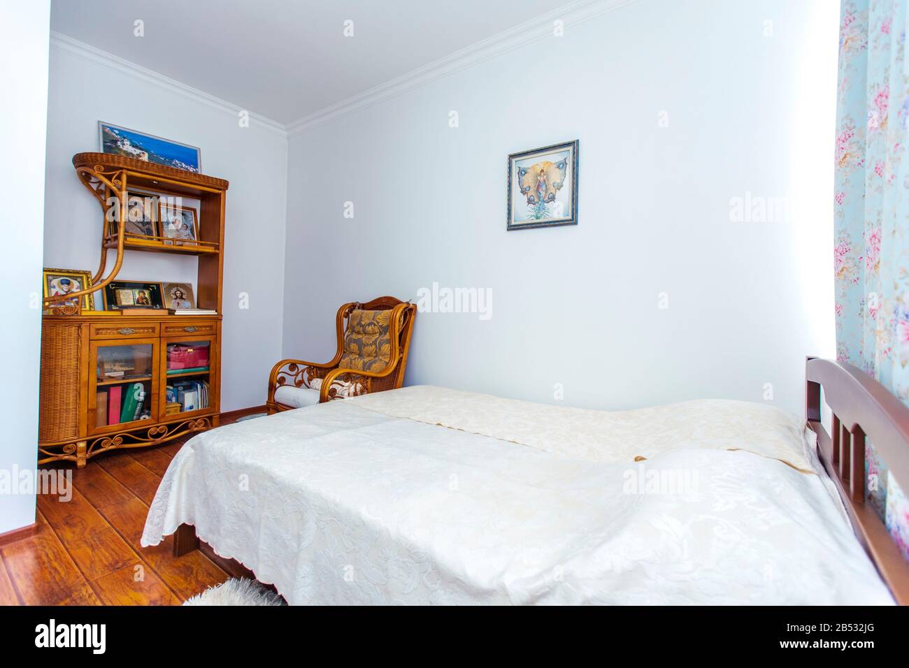 Schlafzimmer mit einem großen Doppelbett aus Holz, einem Schaukelstuhl und vielen christlichen Ikonen auf der Seitenwand gegenüber dem Bett. Stockfoto