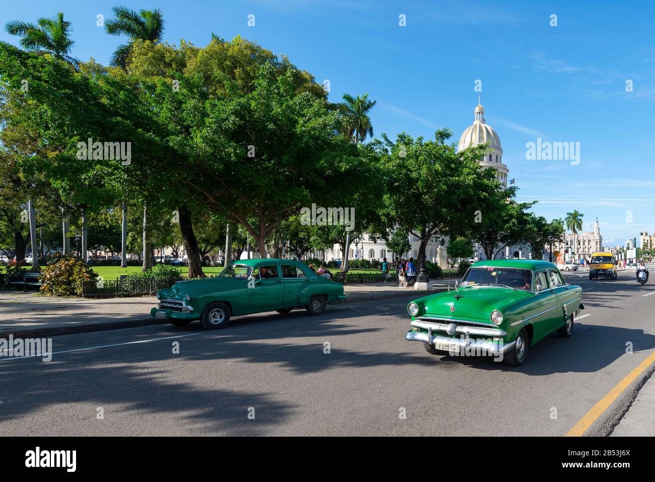 Zwei Oldtimer vor dem American Fraternity Park in Havanna, Kuba. Das Gebäude des Gouverneurs ist bekannt, da El Capitolio dahinter zu sehen ist. Stockfoto