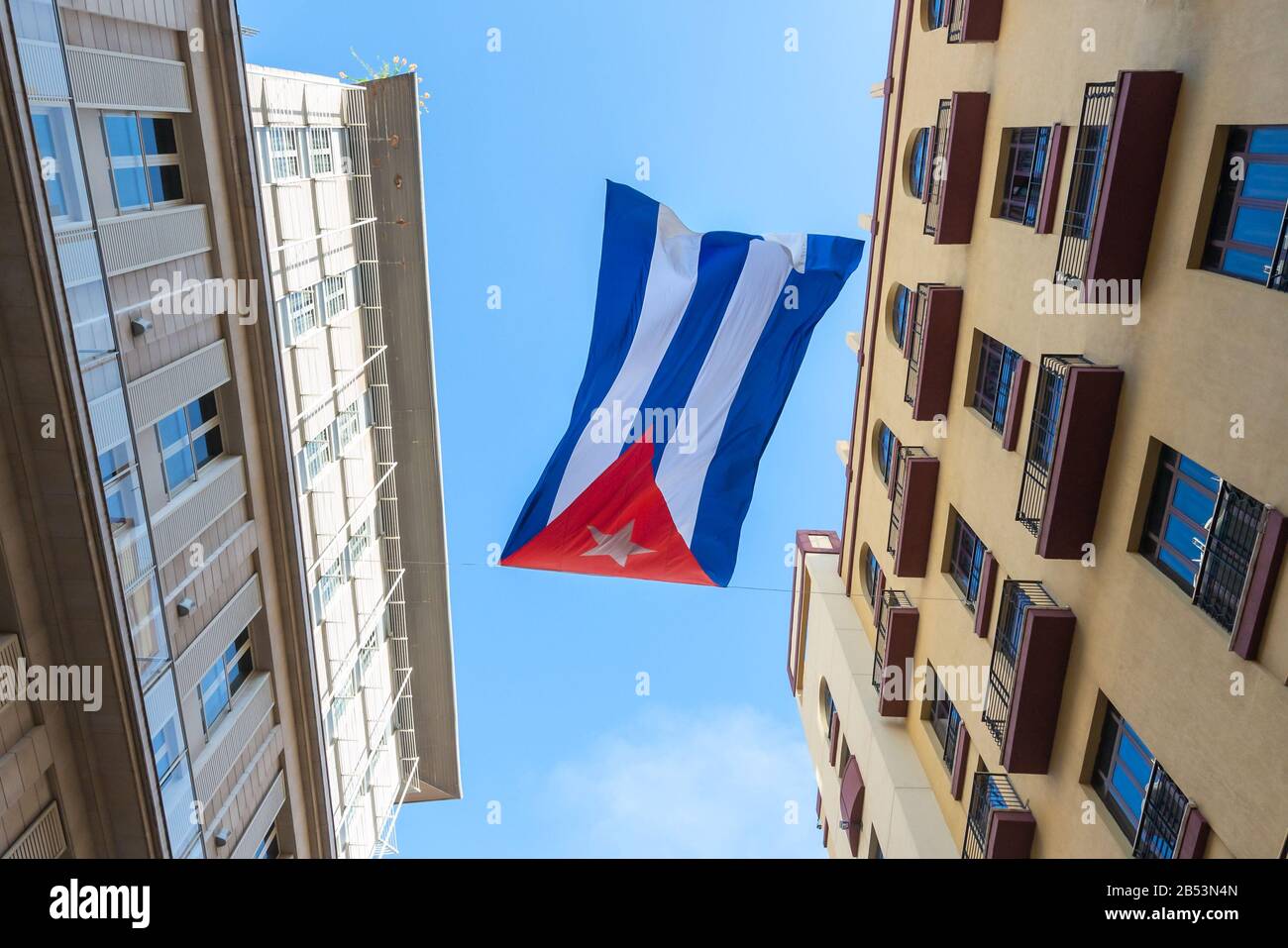 Schwenkende Flagge Kubas zwischen zwei Wohnhäusern in Zentralhavanna, Kuba. Kubaner sind tendenziell sehr patriotisch. Stockfoto