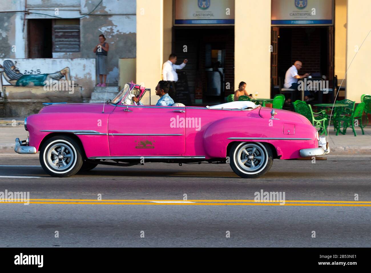 Chevrolet Oldtimer pink ohne Touristen, die vor einem Restaurant in der Malecon Promenade vorbeifahren. Oldtimer mit lebendigen Farben in Havanna, Kuba. Stockfoto