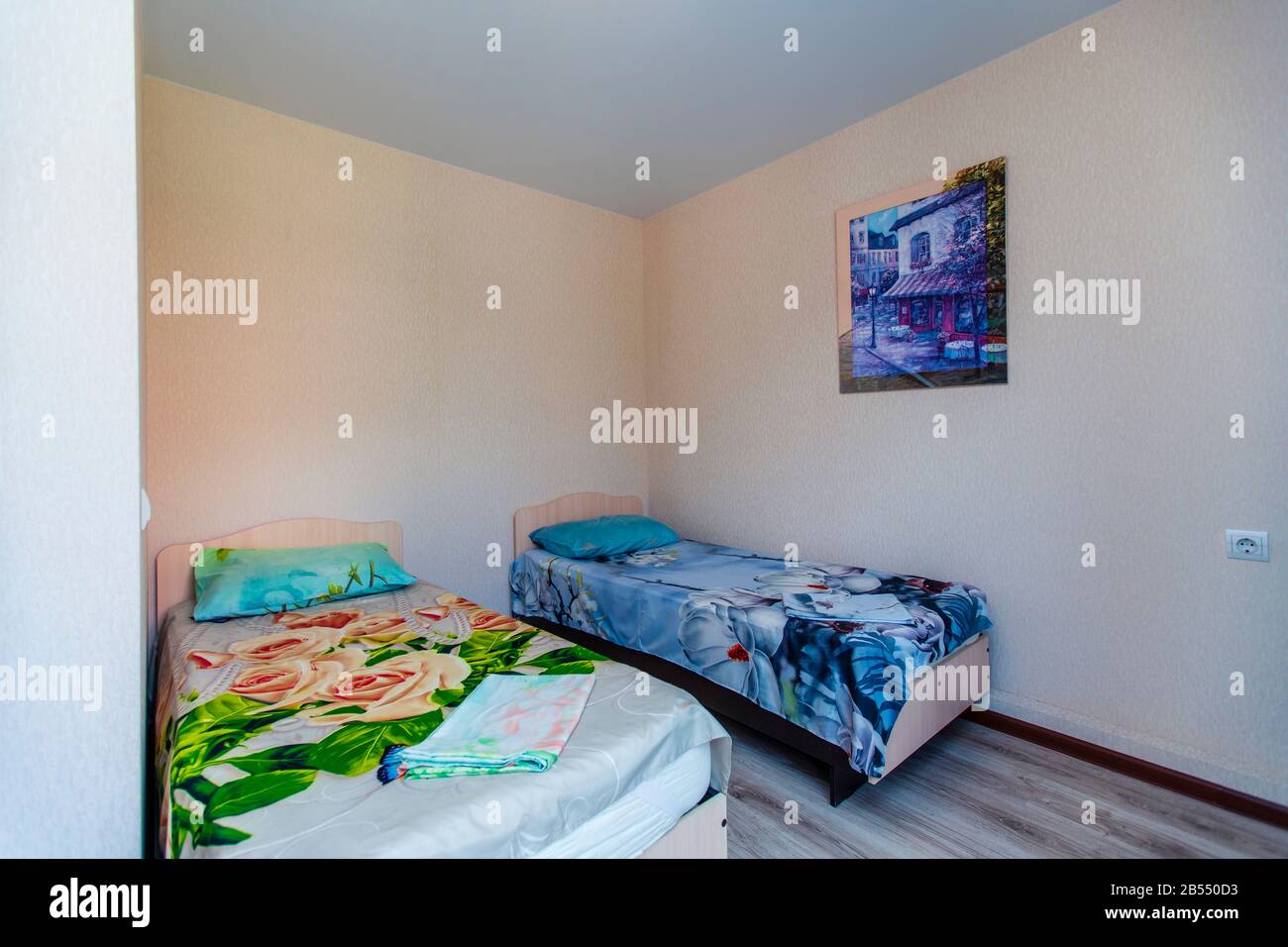 Ein kleines Zimmer in der Pension mit zwei Einzelbetten mit grüner und blauer Bettdecke. Stockfoto