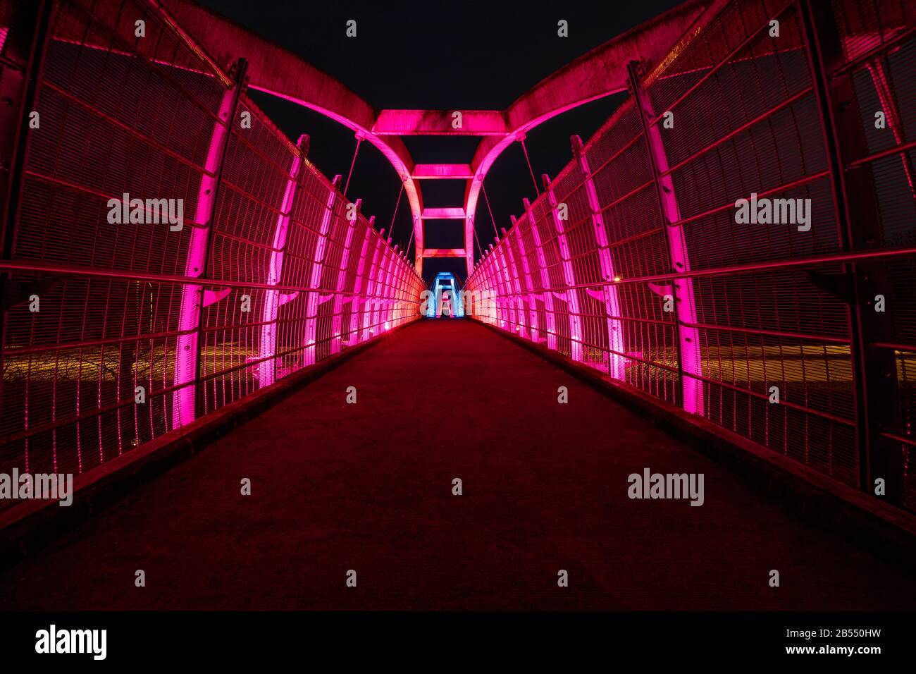 Leuchtend rote LEDs beleuchten nachts den Fußgängerweg über die Autobahn Stockfoto