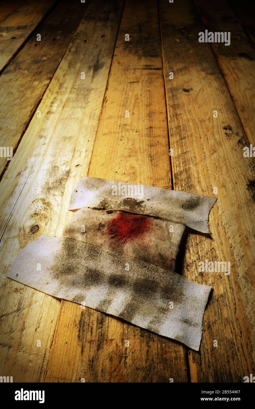 Ein dreckiger Verband auf einem Holzboden. Stockfoto