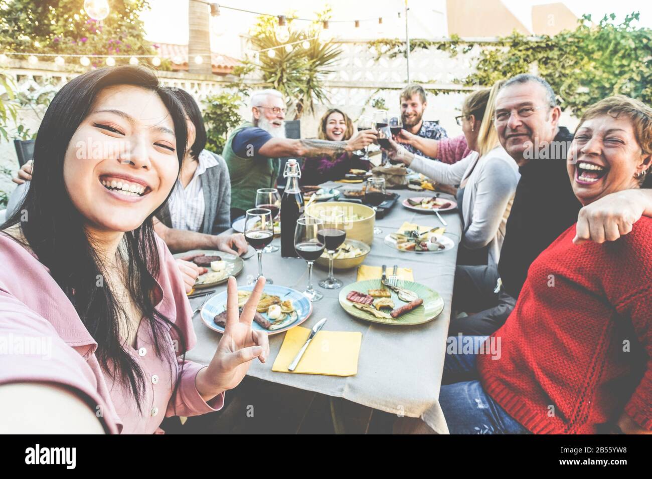 Glückliche Familie und Freunde, die selfie beim Barbecue-Dinner einnehmen - Multirassische Leute, die Spaß beim Essen und Trinken von Wein auf dem Terrassenhaus im Freien haben - Essen und t Stockfoto