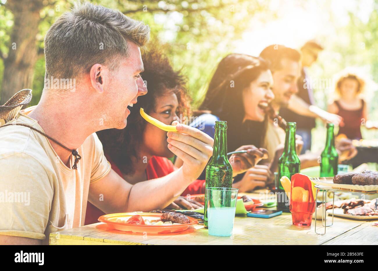 Fröhliche Freunde grillen am Sommertag im Garten im Hinterhof - Junge fröhliche Leute essen leckeres Fleisch bbq Dinner - Konzept über positive Stimmung Stockfoto