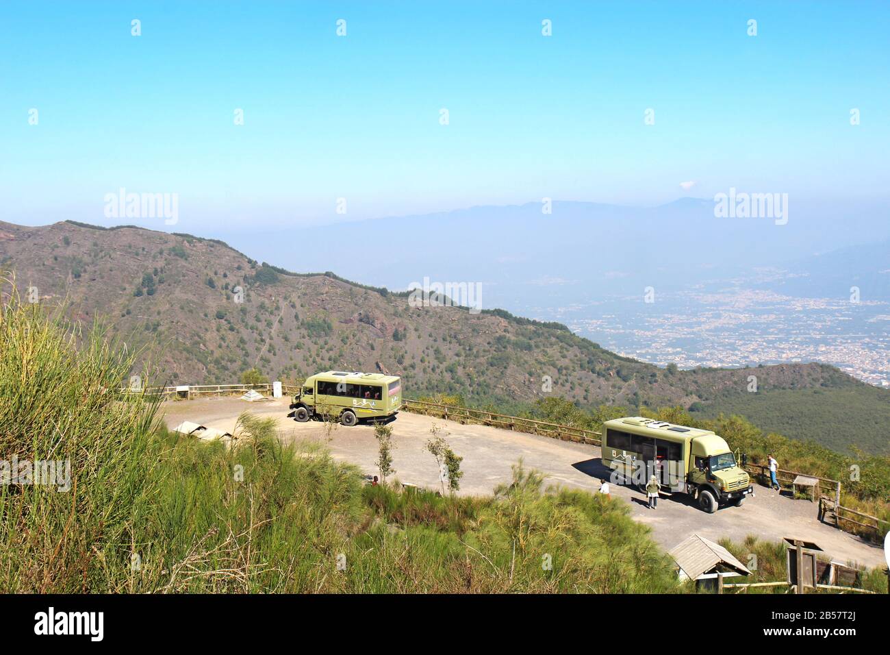 Busse der Busvia del Vesuvio Touren, die am Fuß des Wanderwegs geparkt sind, um zum Gipfel des Schlackenkegels des Vulkans zu wandern. Stockfoto
