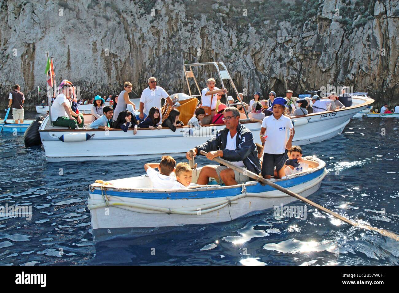 Schulkinder und Touristen in Booten warten auf die berühmte Blaue Grotte auf der Insel Capri. Stockfoto