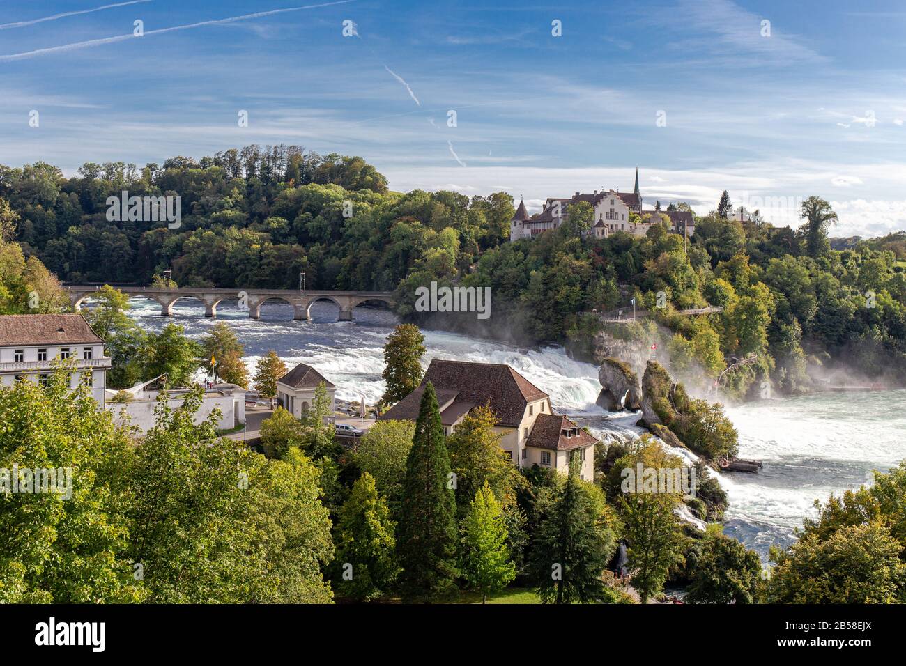 Rheinfall der große und mächtige Wasserfall umgeben von grünem Wald und blauem Himmelshintergrund vom Bahnhof Neuhausen am Rheinfall in swit Stockfoto