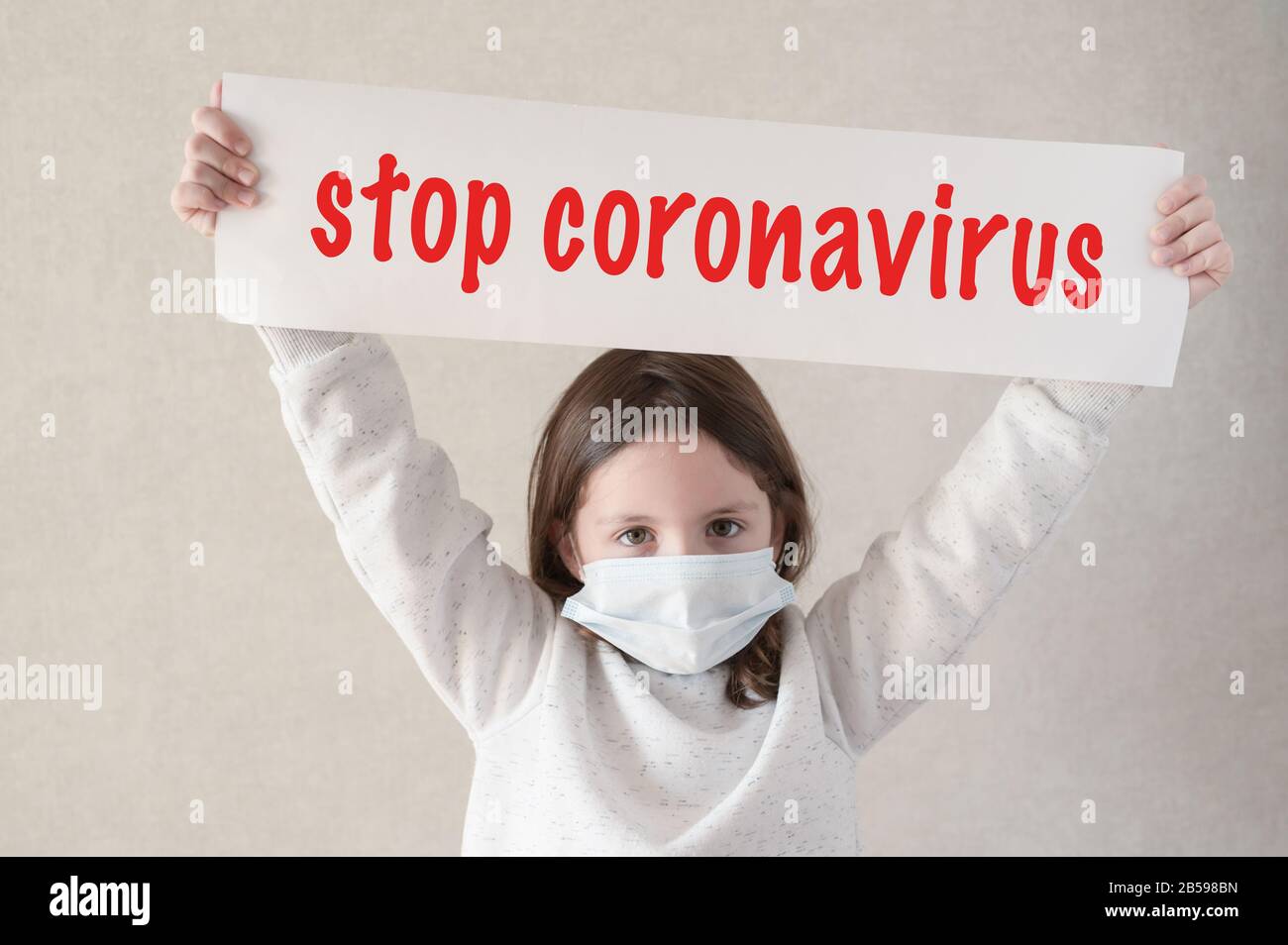 Kovid-19 Epidemie Ausbruch Gesundheitskonzept mit kleinen Mädchen in medizinischer Maske mit Banner mit STOP Coronavirus Slogan Text Stockfoto