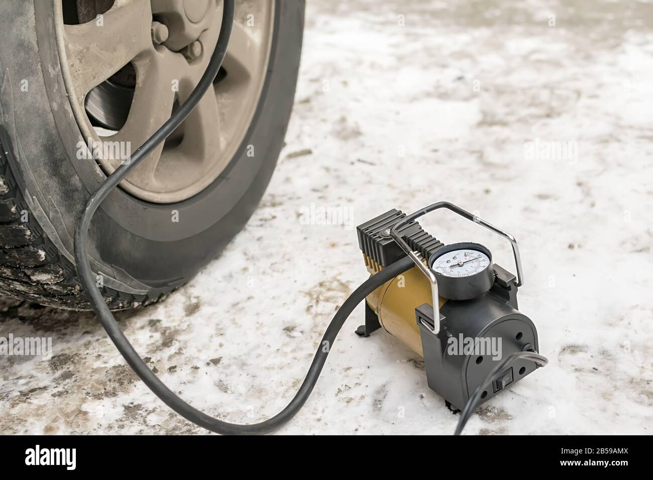 Pumpe, Autokompressor zum Aufpumpen von Reifen mit Luft steht im Winter auf  dem Schnee und pumpt den flachen Reifen des Wagens Stockfotografie - Alamy