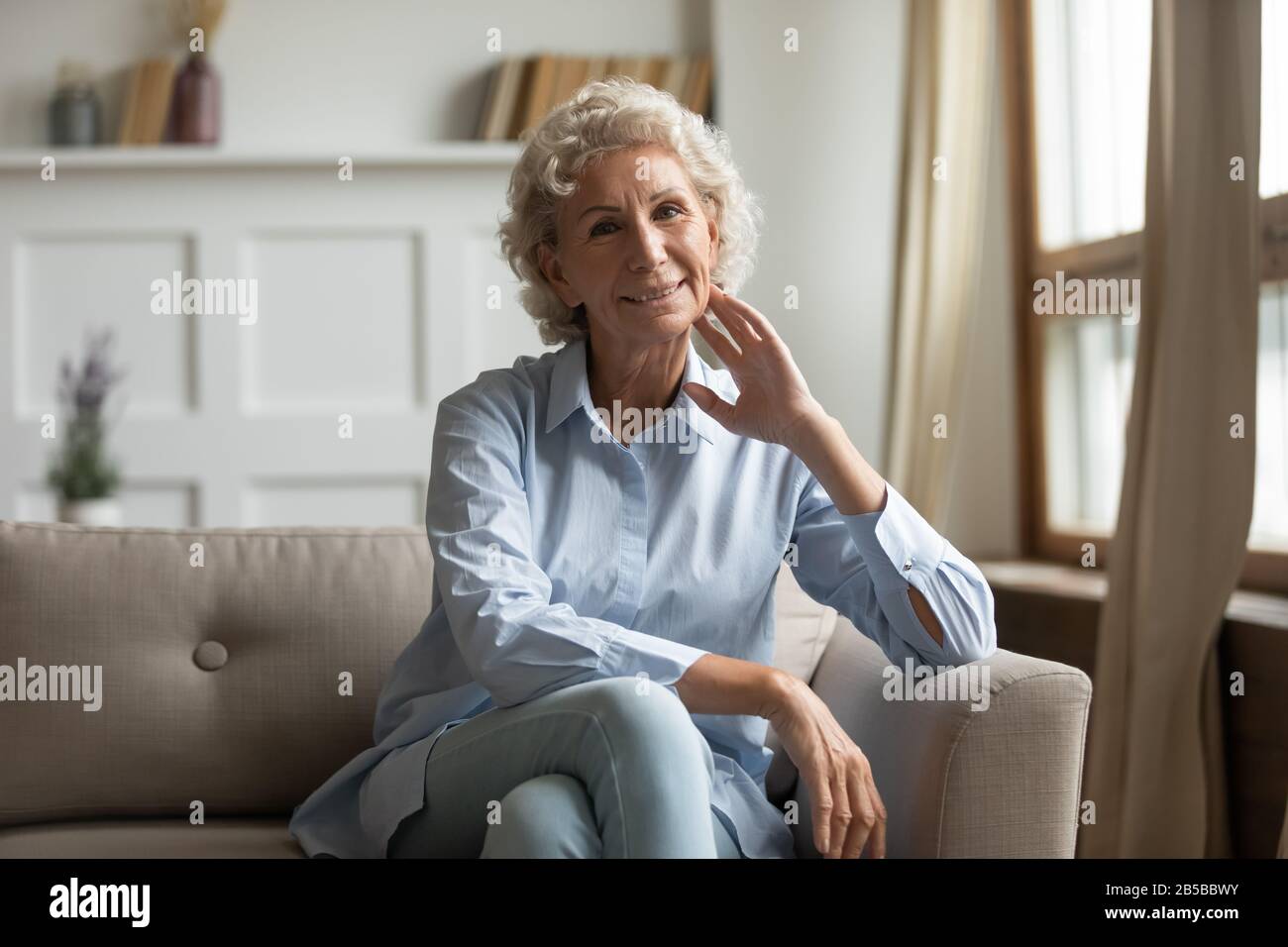 Porträt einer lächelnden Seniorin entspannen Sie sich auf der Couch Stockfoto