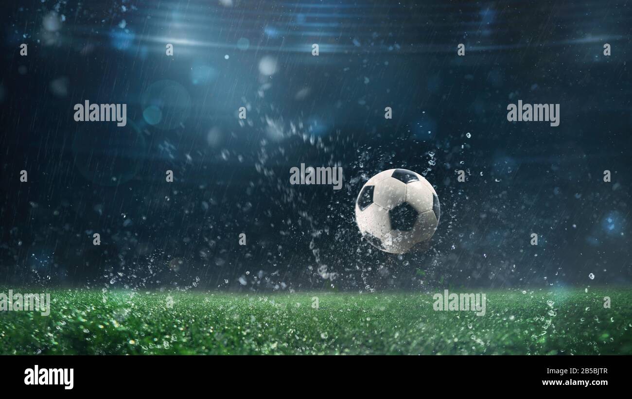 Nahaufnahme eines Fußballballs, der in einer regnerischen Nacht auf dem Spielfeld rollt Stockfoto