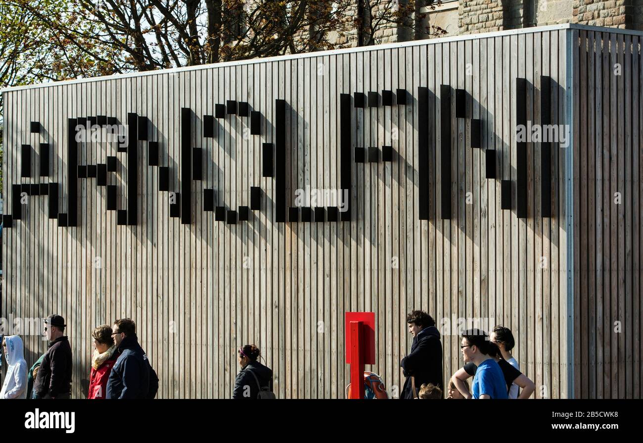 Das optische Täuschungs-Zeichen aus Holz für das Arnolfini Arts Center und die Galerie mit Menschen, die unten vorbeiziehen, Bristol, Avon, England, Großbritannien Stockfoto